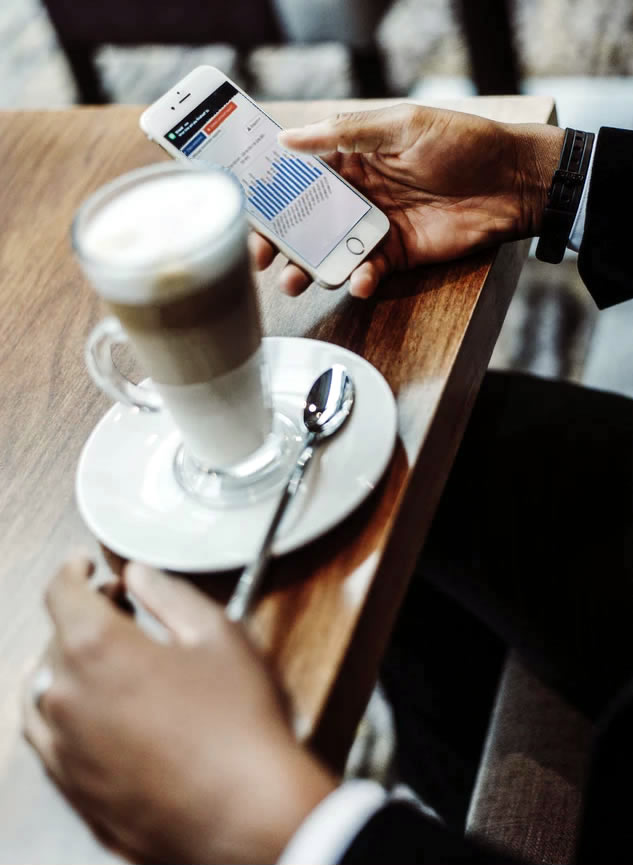 Manager Viewing Reports on Phone with Coffee