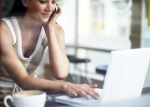 Woman Sitting at Laptop on Phone