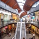 Multi-level Australian shopping centre with escalators and retail stores illustrating real-world store traffic analytics.