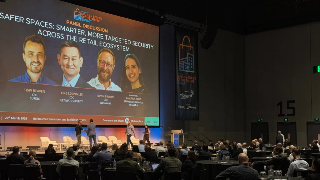 Panel discussion screen at a retail industry conference showing a presentation with a live audience.